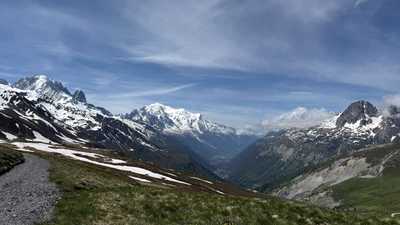Blick von einem Bergweg über ein Tal auf schneebedeckte Gipfel.